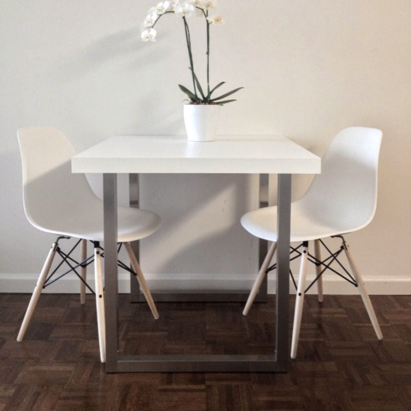 Mesa de comedor blanca con dos sillas y una orquídea encima