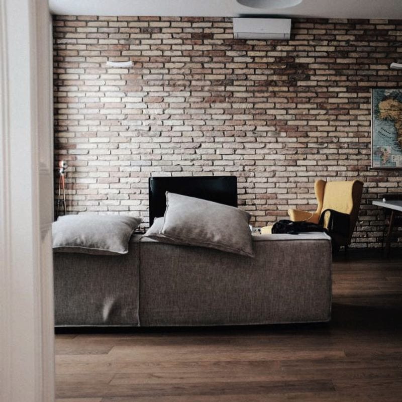 Sofá gris en un salón con una pared de ladrillo visto